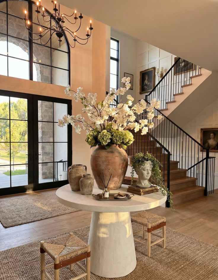 A copper urn of blossom branches on an entryway table by the stairs