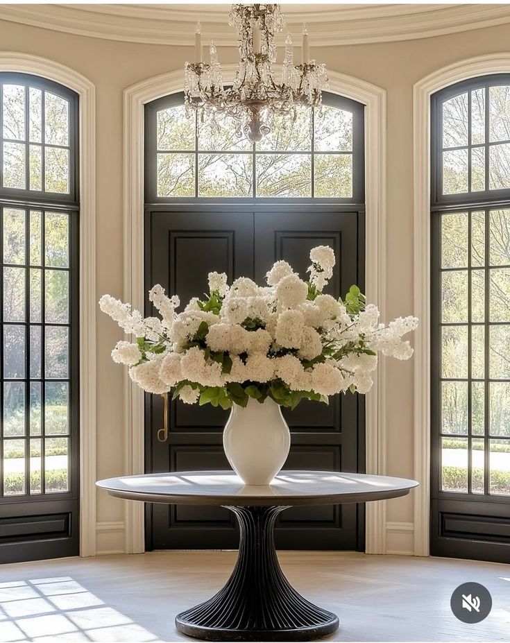 A white vase of hydrangeas on a round foyer table